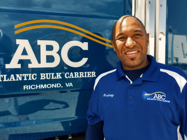 Truck Driver Rodney standing next ot a ABC Truck